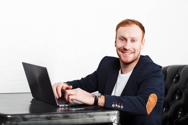 Nuori mies copywriter puku kirjoittamalla kannettavalla tietokoneella ja hymyillen
 - Valokuva, kuva