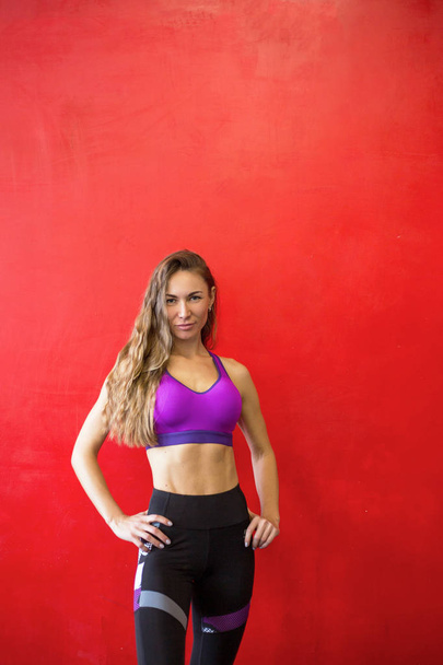 Fit woman is standing near a wall in a gym - Foto, Bild
