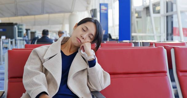 Woman sleep and sit on the check in area in the airport - Photo, image