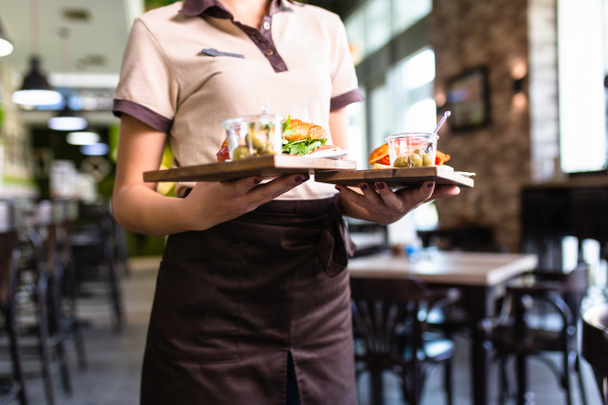 Kellnerin trägt zwei Teller mit Sandwiches. - Foto, Bild