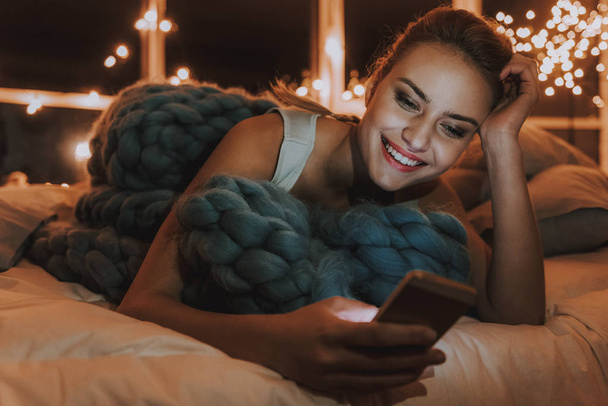 Счастливая молодая женщина смотрит на мобильный телефон
 - Фото, изображение