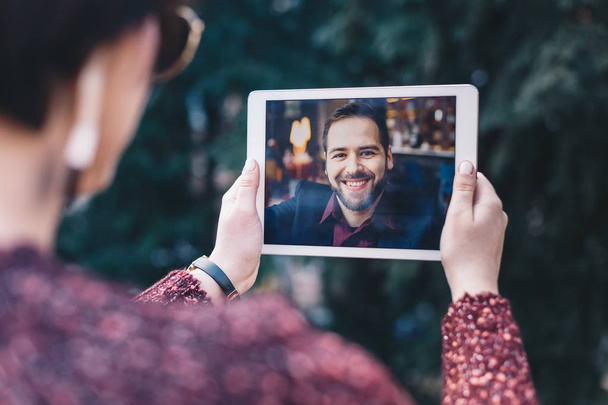 Young woman using a tablet by having a video call chat with her businessman boyfriend who is away on a business trip. Concept of keeping a long distant relationship in a career oriented world. - Photo, Image