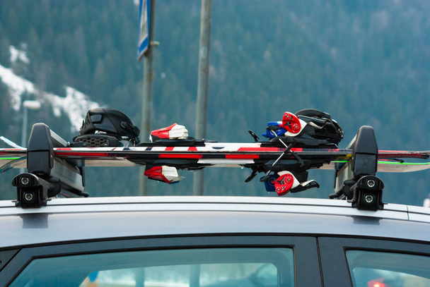 Две пары лыж и сноуборд на крыше автомобиля - Фото, изображение