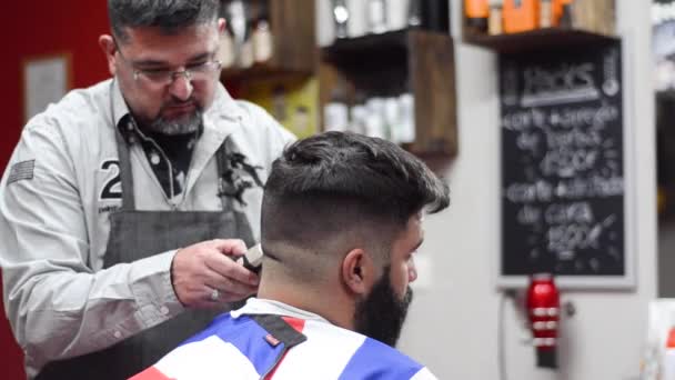 Hombre barbudo guapo consiguiendo corte de pelo por peluquería en la peluquería
. - Metraje, vídeo