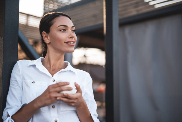 Dreamy lady looking away and smiling while drinking coffee - Foto, Imagem