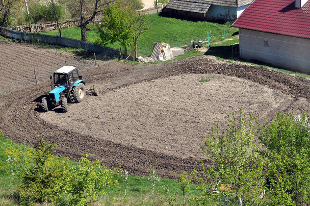Sur une terre agricole, un tracteur à roues avec un cultivateur prépare le sol pour semer les cultures de printemps
 - Photo, image
