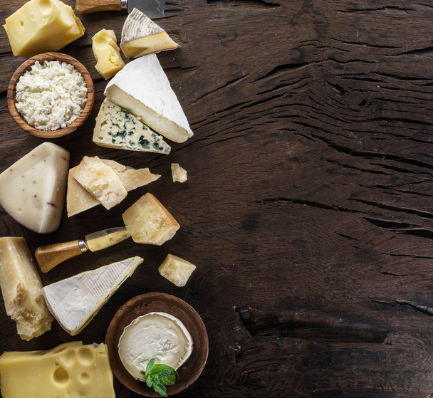 Assortment of different cheese types on old wooden background. Top view. - Фото, изображение