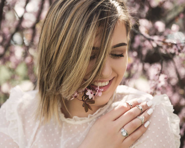 Portrait of young woman posing with cherry tree flowers - Foto, Imagen