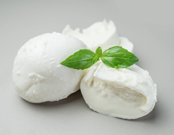 Traditional Italian mozzarella cheese with herbs on gray background. - Foto, afbeelding
