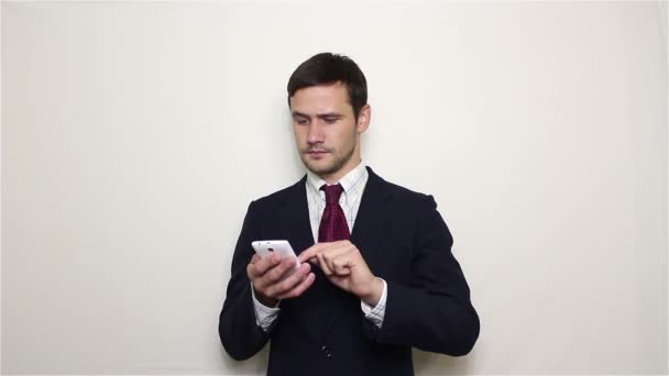 Young handsome businessman pulls out his smartphone from his pocket and looks through the news feed. - Filmati, video