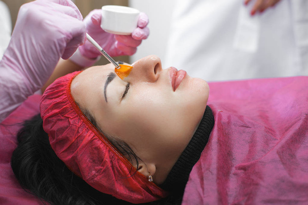 Cosmetologa fare un massaggio al viso al suo paziente e una maschera per il viso. Procedura anti-invecchiamento e levigante in un salone di bellezza. Medico in una clinica cosmetologica facendo un trattamento di cura della pelle - Foto, immagini