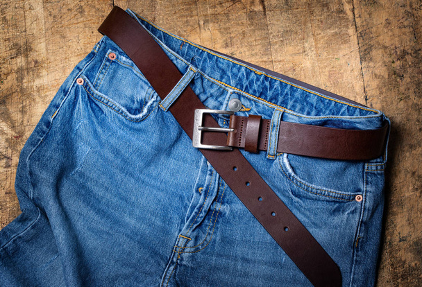 blue jeans with belt on old wooden texture .background - Photo, Image