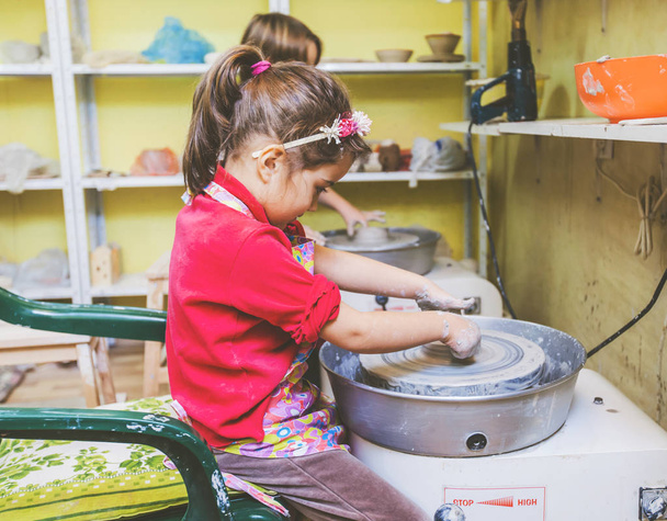 Little girl creative learning at potter workshop - Child shaping clay on pottery wheel  - Valokuva, kuva