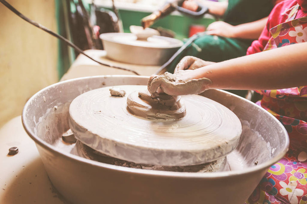 Manos de alfarero joven formando jarrón de cerámica con arcilla en la rueda de cerámica en el taller
 - Foto, imagen