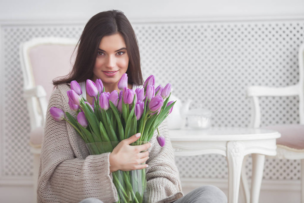Close up portrait of young beautiful woman indoors. Attractive woman with flowers. Female with tulips. Spring bouquet. - Fotografie, Obrázek