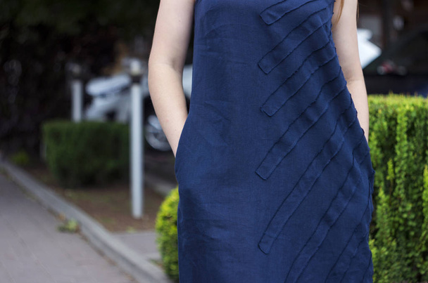 Fiatal nő sötét kék vászon ruhát tartja kezében a zsebek, nyár, divat - Fotó, kép