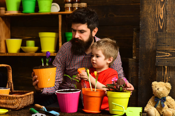 Flower watering. Soil fertilizers. Father and son. Fathers day. Family day. Greenhouse. man and little boy child love nature. happy gardeners with spring flowers. I like taking care of the flowers - Фото, изображение