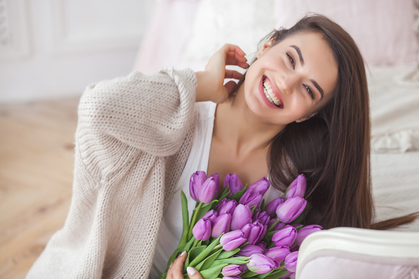 Close up ritratto di giovane bella donna all'interno. Donna attraente con fiori. Donna con i tulipani. Bouquet di primavera
. - Foto, immagini