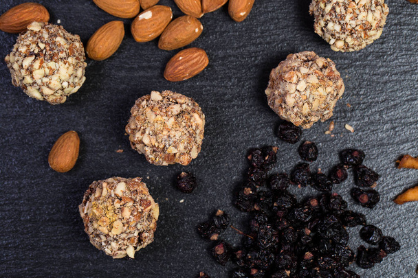 Theme is a sweet dessert made from natural products without sugar. Macro close up closeup dessert sweet candy round ball handmade truffle dried fruit set of almonds dried pear and honey. - Photo, Image