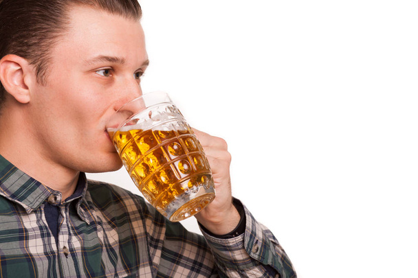 Recortado de cerca la toma de estudio de un joven guapo disfrutando de beber cerveza aislado en blanco. Hombre atractivo bebiendo cerveza alegremente del vaso, copia el espacio en el lateral. Ocio, concepto de fin de semana
 - Foto, Imagen