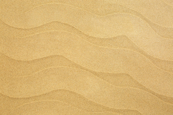 Beach sand with wave flows forming an abstract background. Top view. - Photo, Image
