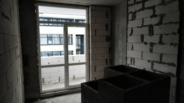 Κατασκευή από ένα διαμέρισμα πολυόροφων κτιρίων από πορομπετόν. Θέα από το κτισμένο διαμέρισμα μέσα στο νεόδμητο κτήριο πολυόροφων κτιρίων. Κενούς τοίχους των νέων κτιρίων από το μπλοκ του φυσικού αερίου. - Φωτογραφία, εικόνα