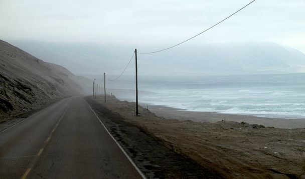 Üres út mellett az óceánt egy Ködös reggel a hegyek a háttérben. Pan amerikai Highway, fénykép elvett a perui út része - Fotó, kép