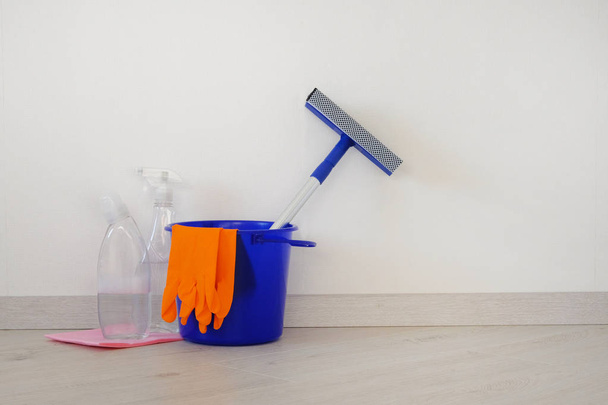 Housework and housekeeping concept. Bucket with cleaning agents, rubber protective glove and blue mop at home. - Fotó, kép