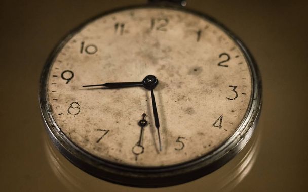 un viejo reloj de bolsillo antiguo con una esfera amarillenta sobre un fondo grunge vintage. Las manos indican que es a las 8: 30. Enfoque selectivo
. - Foto, Imagen