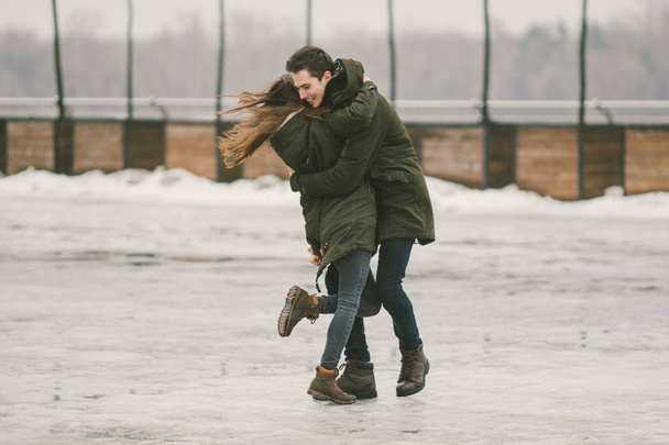 Bir heteroseksüel çift gençlerin aşk öğrenciler bir adam ve beyaz bir kadın. Buzla kaplı Kış, kentin kare, onlar yürümek, sarılmak ve öpmek. Aşk kavramı herhangi bir hava. - Fotoğraf, Görsel