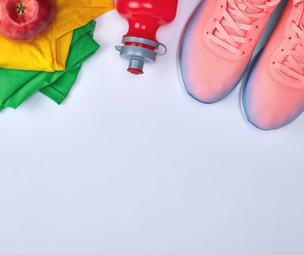 pink sports sneakers and green clothes on a white background, copy space - Photo, Image