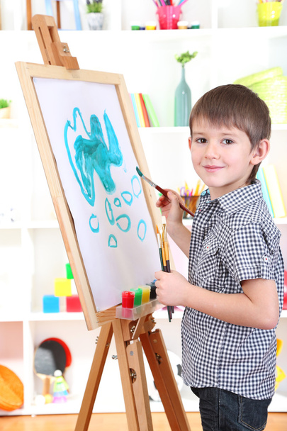 Little boy painting paints picture on easel - Fotoğraf, Görsel