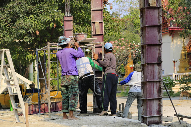De bouw-technicus is bezig met het gieten van de betonnen pijlers. - Foto, afbeelding