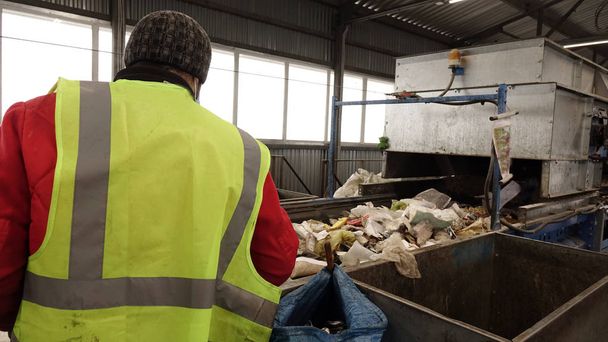 Trabajadores de la planta de tratamiento de residuos. Clasificación de la basura en una cinta transportadora
 - Foto, Imagen