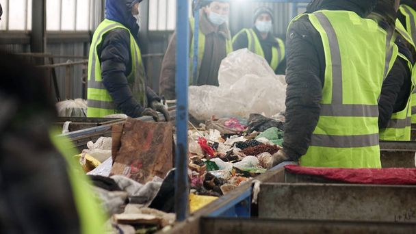 Jätteenkäsittelylaitoksen työntekijät. Roskien lajittelu kuljetinhihnalla
 - Valokuva, kuva