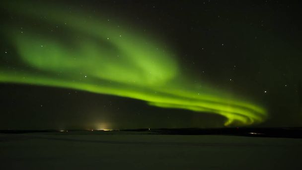 Północnej polarną (aurora borealis) w horyzoncie powyżej Ivalo od Saariselka w fińskiej Laponii. - Zdjęcie, obraz