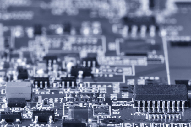 Printed circuit board close up for background Microchips and other components Small depth of field Toned image - Fotó, kép