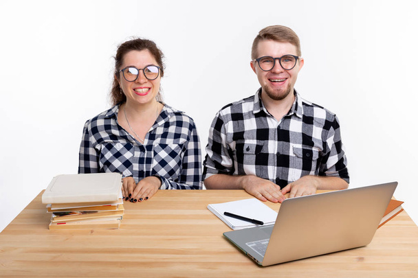 Education, students, people concept - funny couple of teens in glasses look like nerds sitting at the table - Photo, Image