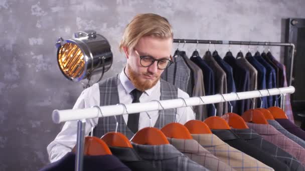Junger Mann mit Bart wählt Anzug in einem Geschäft - Filmmaterial, Video