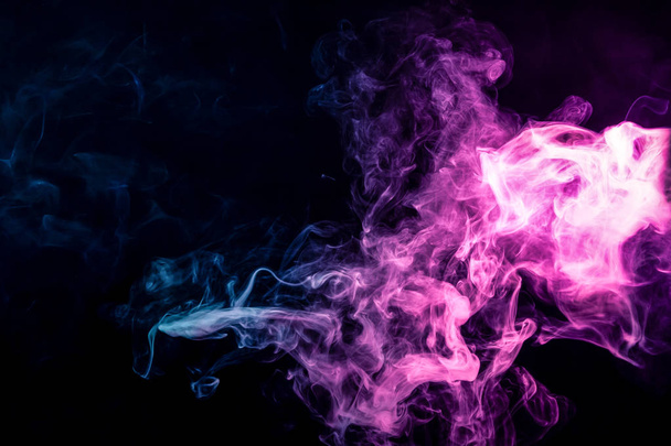 Dense multicolored smoke of   blue and purple colors on a black isolated background. Background of smoke vap - Photo, Image