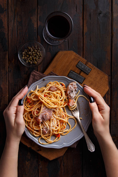 Spaghetti z kawałkami świeżego tuńczyka, pomidor i kapary na ciemnym tle - Zdjęcie, obraz