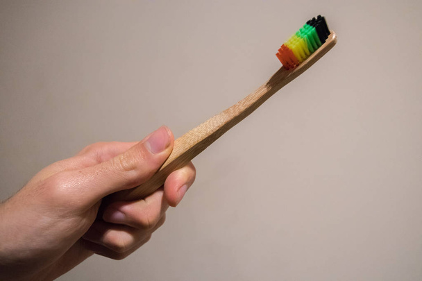 Μπαμπού οδοντόβουρτσα ηθικές βούρτσα με rasta χρώματα κρατώντας στο χέρι - Φωτογραφία, εικόνα