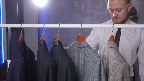 Giovane uomo elegante sceglie abito classico in negozio
 - Filmati, video