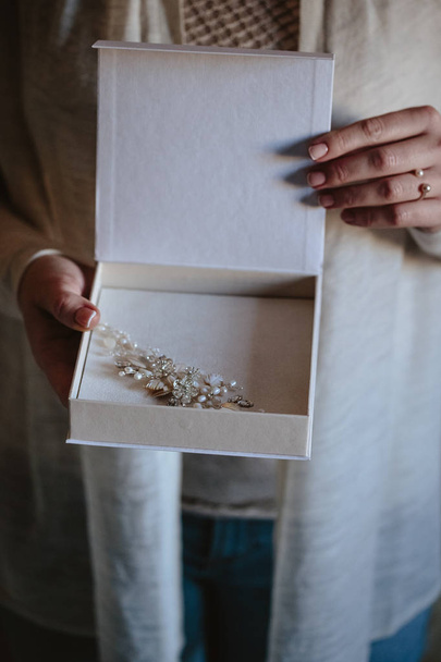 Woman's hands hold a white blank box with wedding handmade jewelry inside - Фото, зображення