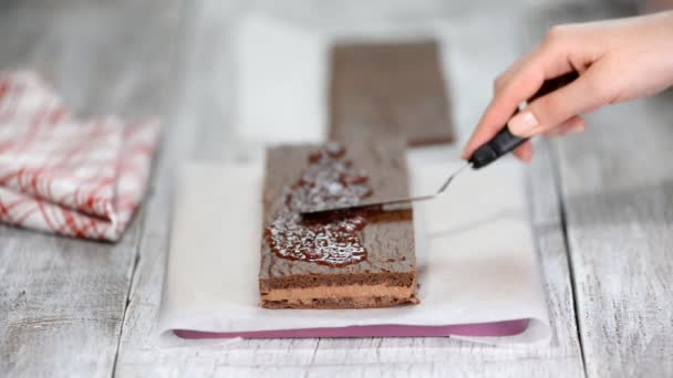Koch macht Schicht Schokoladenkuchen mit Himbeermarmelade. - Filmmaterial, Video