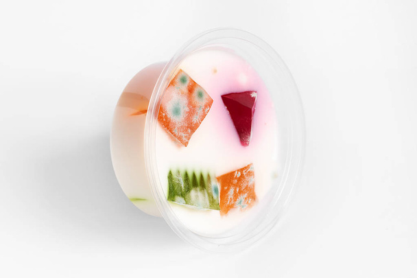 плесень грибов на цветном мармеладе в молочном желе, просроченные продукты питания, белый фон
 - Фото, изображение