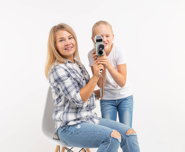 Fotoğraf, fotoğrafçı ve retro kamera kavramı - genç kadın ve genç kızı beyaz arka plan üzerinde vintage fotoğraf makinesi kullanma - Fotoğraf, Görsel