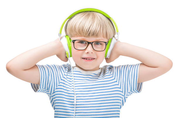 Šťastné dítě nosit sluchátka. Roztomilý kluk na izolované bílém pozadí poslechu hudby pomocí sluchátek a usmívá se - Fotografie, Obrázek
