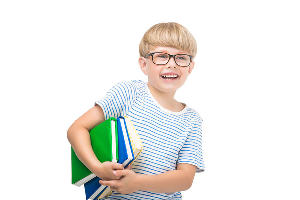 Cute little child with books and notebooks on isolated white background. Adorable kid reading. Schoolboy studio shot. Boy wearing eyeglasses. - Fotografie, Obrázek