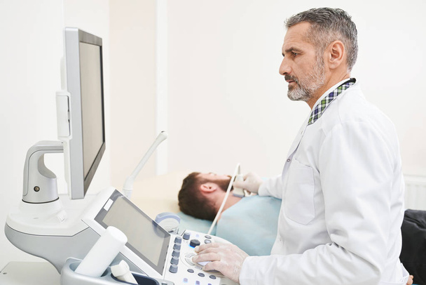Doctor sitting, looking at screen, doing diagnosis of neck. - Valokuva, kuva